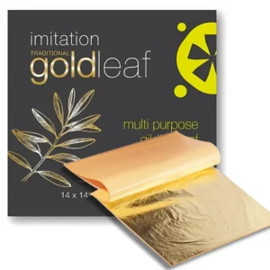 There is an open pad of Prime Art Imitation Gold Leaf in the front left hand corner of the frame, some of the sheets are folded over to reveal more of the pad. There is a full pack in the top right hand corner of the frame, behind the open pad. On a white background.