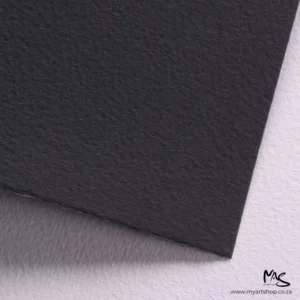A close up of a corner of a sheet of Black Fabriano Cromia Paper can be seen filling the frame. You can see a slight texture in the paper. The image is cut off by the frame.