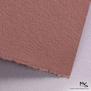 A close up of a corner of a sheet of Pale Brown Fabriano Cromia Paper can be seen filling the frame. You can see a slight texture in the paper. The image is cut off by the frame.