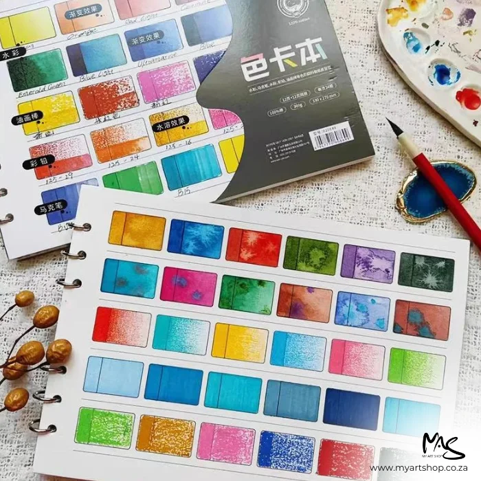 There is a Potentate Artists Colour Diary with the ringbinder open, coming out of the right hand side of the frame. There are spare sheets in the background. The top sheet of the ringbinder has already been coloured in.