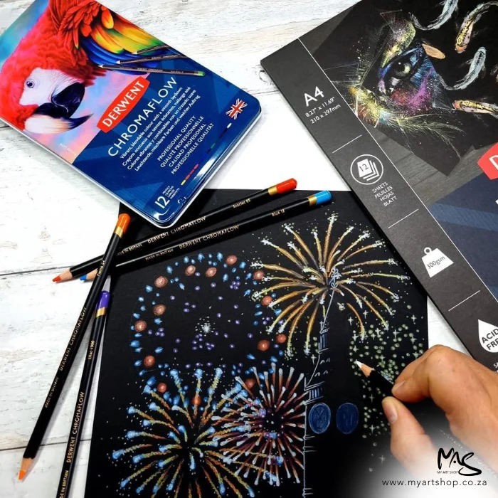 derwent-chromaflow-pencil-set-12s-05 A promotional image containing a Set of 12 Derwent Chromaflow Pencils laying on a drawing of fireworks that has been made on black paper using the pencils from the set. The image is cut off by the frame.