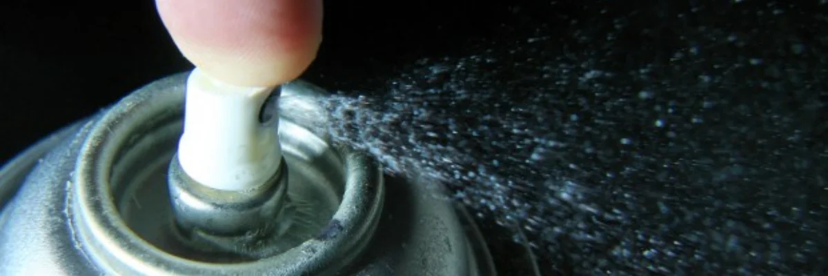 Preserve Your Masterpieces Discover the Best Matte Fixative Spray is shown being sprayed across the image as someone is pushing down on the nozzle it is forcing a hard spray of fixative to come out with a force. the can is only visable from the top which is silver and the nozzle is white. the background is black to show off the effect better.