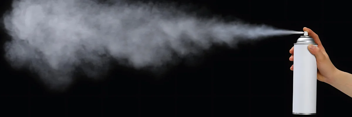 Say Goodbye to Messy Glue: Find Your Perfect Spray Adhesive for Paper is shown by the spray effect going across the top of the image from right to left. the thin mist og glue pray is seen as a very light almost translulscent mist infront of a very black background.