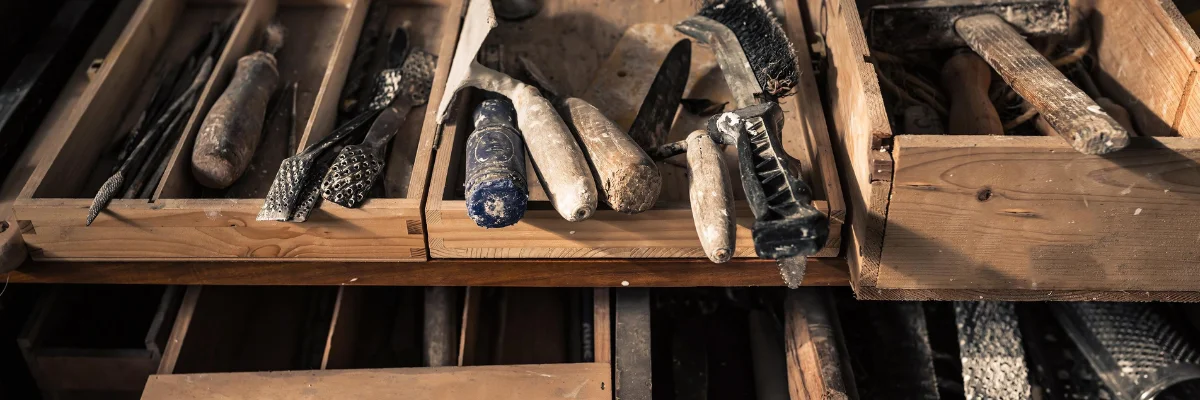 The Ultimate Guide to Clay Sculpting Tools Fun and Functional! is showing in the picture a variety of tools that have been used and are placed inside of a wooden storage box haphazardly. they are many different types of tools and have been well used and are covered in bits of clay.. the box is a wooden box. in the center of the image