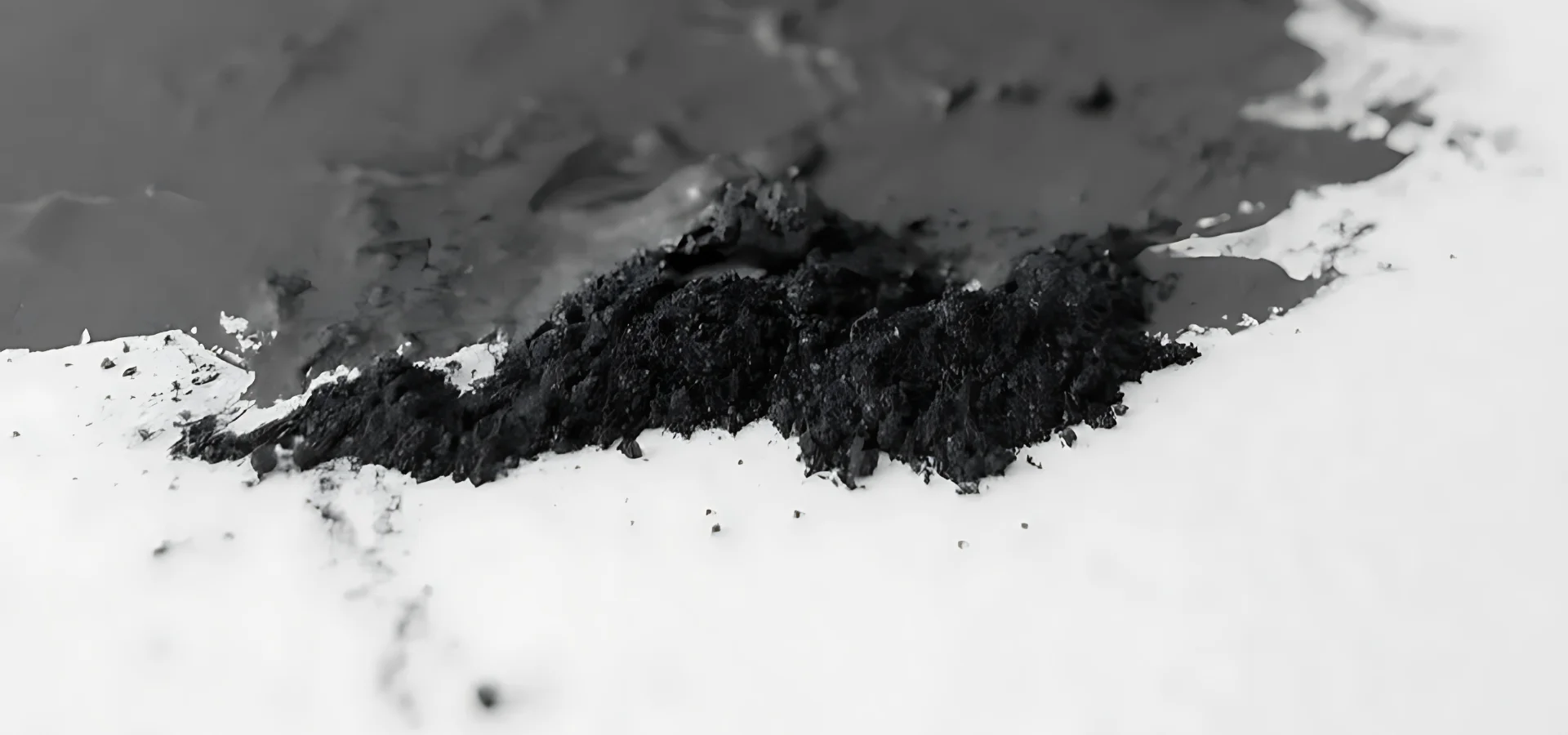 ArtGraf Water Soluble Graphite Powder Sack. Graphite powder poured onto a piece of paper. Dry powder at the front and wet powder towards the back