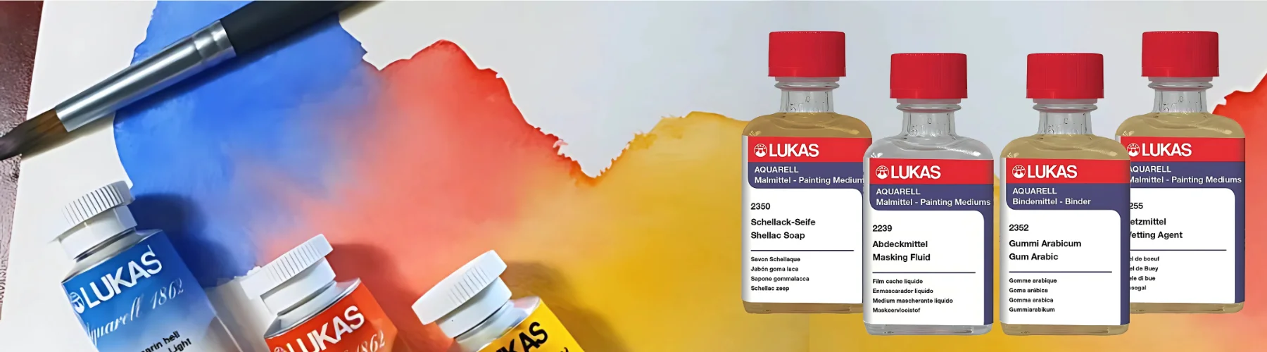 lukas-watercolour-mediums-dive-into-colour, on the left of the image there is a paintbrush that is resting on the watercolour paper. along the bottom are three tubes of paint all lined up, blue, red and yellow. there is watercolour paint above them in the same colours. on the right hand side are four bottle of lukas watercolour medium all lined up. they are glass bottles with red and blue labels and red lids