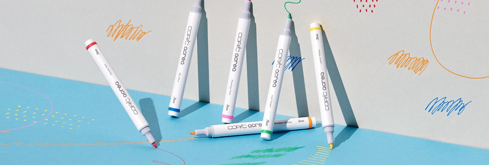 acrea-paint-markers-splash-scribble-create. There are 6 Copic Acrea Paint Markers shown in the frame. They are standing up against a wall that has been drawn on using the markers.
