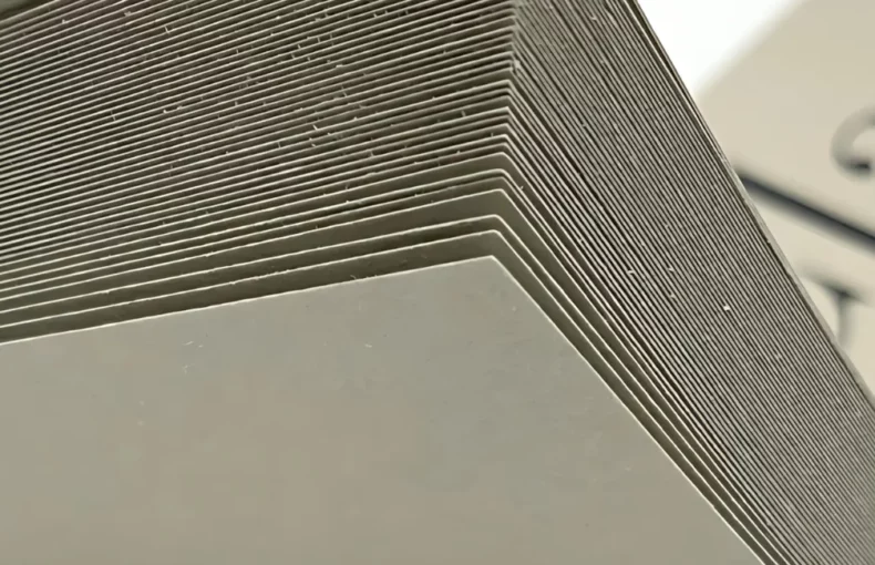 fabriano-toned-paper-drawing-dazzle. the image is of a close up of a fabriano pad. clay. it shows all the sheets being pulled up. and you can see the name of the pad in the bakcground