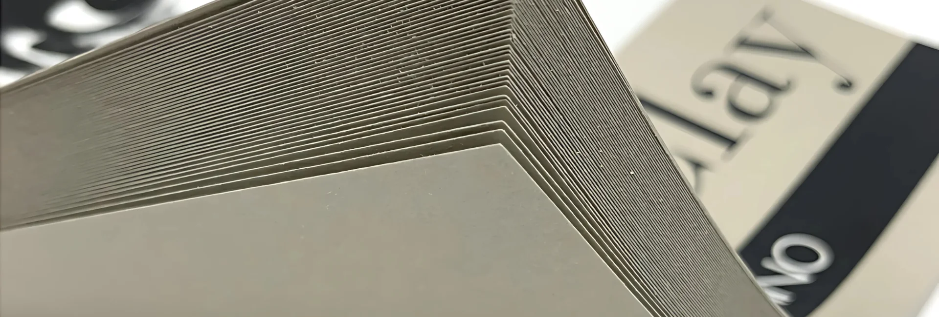 fabriano-toned-paper-drawing-dazzle. the image is of a close up of a fabriano pad. clay. it shows all the sheets being pulled up. and you can see the name of the pad in the bakcground