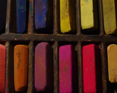 soft-pastels-get-artsy-with-it. the image shows a close up of a set of soft pastels that are in a rainbow order. there are many small pastels visable in the image. and they have been used, so some are smaller than others