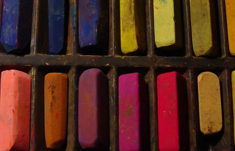 soft-pastels-get-artsy-with-it. the image shows a close up of a set of soft pastels that are in a rainbow order. there are many small pastels visable in the image. and they have been used, so some are smaller than others