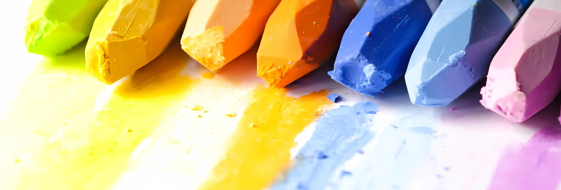 water-soluble-pastels-for-art-enthusiasts. the image shows a close up of a variety of different colours of oil pastels that are at the top of the image. they have their own colour laid down on the paper infront of them. they are in a rainbow colour order and are brightly coloured pastel sticks